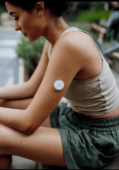 Woman outdoors wearing a continuous glucose monitor sensor on her upper arm