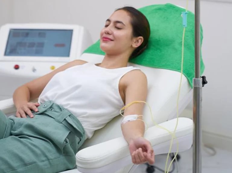 A woman reclining in a treatment chair during an intravenous infusion