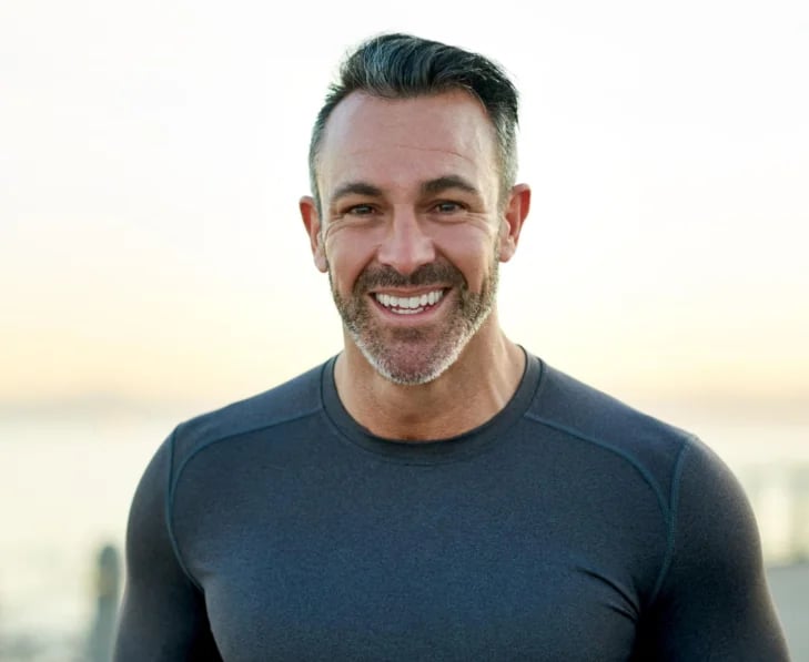 A man smiling outdoors at sunset — choosing between testosterone pellets and injections