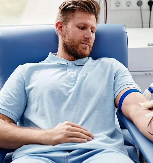 Man seated in a donation chair during a blood draw